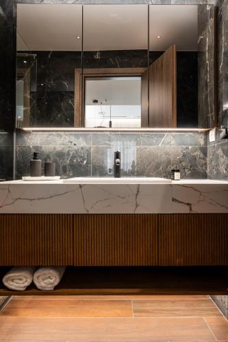 une salle de bain avec un lavabo et un miroir dans l'établissement Omikron Luxury Residences, à Héraklion