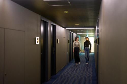 two women walking down a corridor in a hallway at Hotel Resol Kyoto Shijo Muromachi in Kyoto