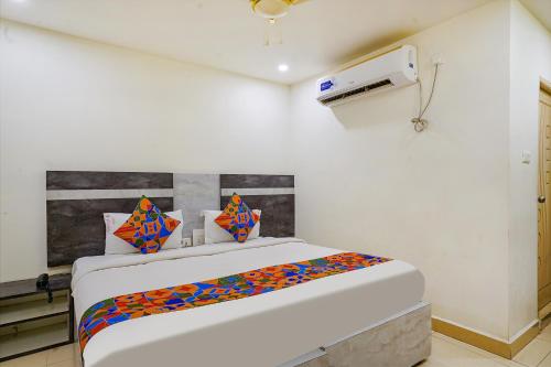 um quarto branco com uma cama com almofadas coloridas em FabHotel Ambika Elite em Vijayawada
