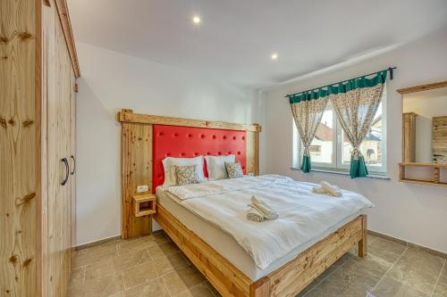 a bedroom with a large bed with a red headboard at Apartments Viktor in Rateče