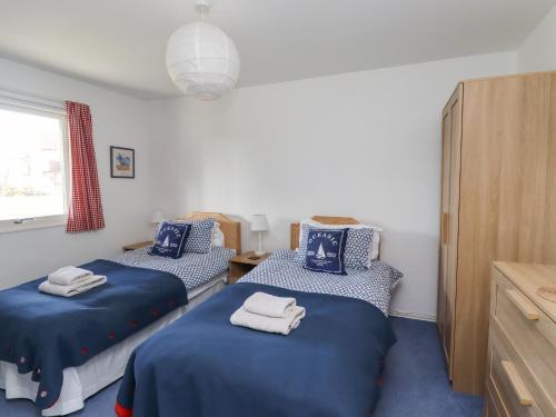 um quarto com 2 camas azuis e uma janela em Beachside Beadnell em Beadnell
