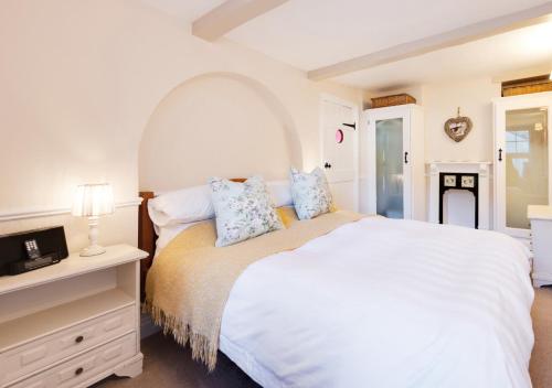 a bedroom with a large white bed and a dresser at Jasmine Cottage in Brixham