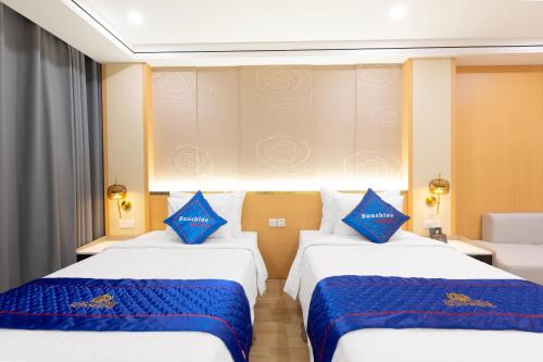 2 camas en una habitación de hotel con almohadas azules en Sunshine Apartment Hotel en Móng Cái