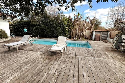 zwei Stühle auf einer Terrasse neben einem Pool in der Unterkunft Villa COLIVING EFFET MER - Nomad Digital - 4 chambres in Anglet