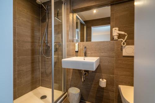 ein Bad mit einem Waschbecken und einer Dusche in der Unterkunft Hotel Weißbräu in Oberhaching
