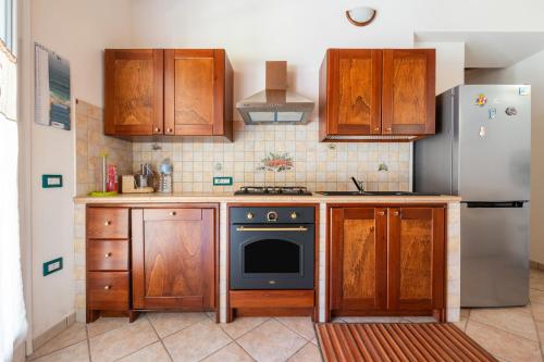 a kitchen with wooden cabinets and a refrigerator at Casa Vacanza Ghisu in SantʼAnna Arresi