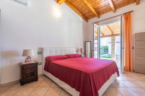 a bedroom with a bed with a red bedspread at Casa Vacanza Ghisu in SantʼAnna Arresi