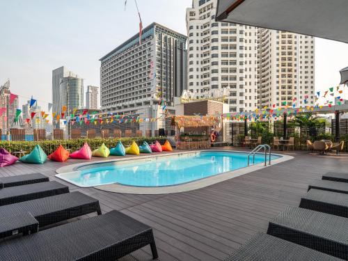a swimming pool with colorful pillows next to a city at VELA Dhi GLOW Pratunam in Bangkok