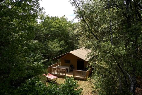 une cabine avec terrasse couverte au milieu d'une forêt dans l'établissement Glamping Les Eyzies, à Carmensac