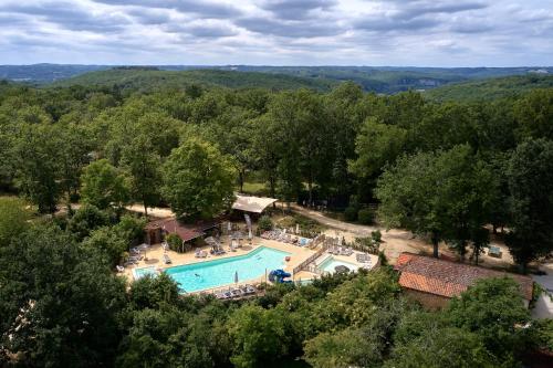 - une vue aérienne sur une piscine bordée d'arbres dans l'établissement Glamping Les Eyzies, à Carmensac