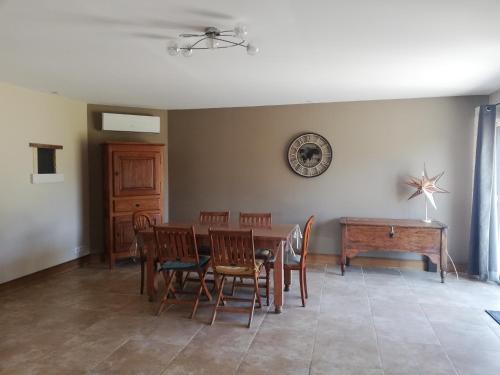 a dining room with a table and chairs and a clock on the wall at La Grange de la Chaise in Saint-Georges-sur-Cher