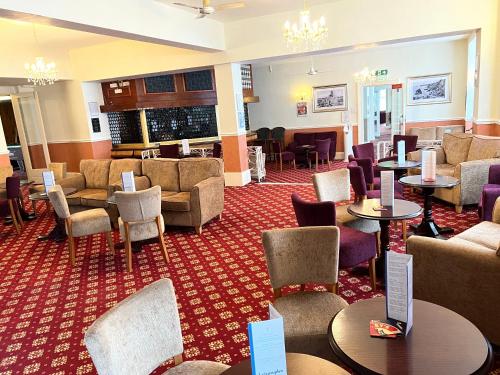 a hotel lobby with tables and chairs and a waiting room at Eliot Hotel in Newquay