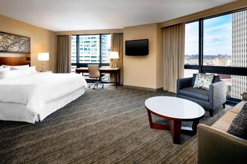 a hotel room with a bed and a couch and a table at The Westin Cincinnati in Cincinnati