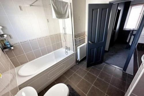 a bathroom with a tub and a toilet and a sink at Green Haven Villa - 4BR Spacious House with Hot tub, Ample Parking, Air Condition, WIFI, Netflix, Patio & Garden in Kidlington