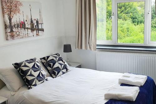 a bedroom with a white bed with two towels on it at Green Haven Villa - 4BR Spacious House with Hot tub, Ample Parking, Air Condition, WIFI, Netflix, Patio & Garden in Kidlington