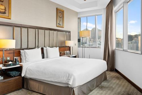 a bedroom with a large bed and a large window at Holiday Suites Al Azizia in Makkah