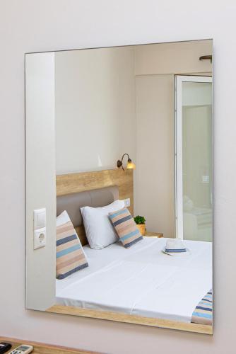 a mirror reflecting a bed in a bedroom at Theo Star Beach Hotel in Malia