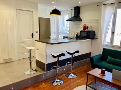 Le Nivolet, cosy appartement في شامبيري: مطبخ مع كونتر وكراسي في غرفة المعيشة