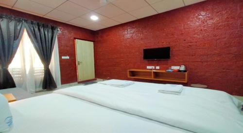 a bedroom with a large bed and a television at West Coast Gokarna in Gokarna
