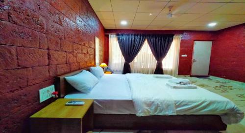 a bedroom with a large bed and a brick wall at West Coast Gokarna in Gokarna