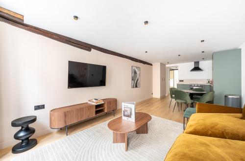 un salon avec un canapé et une télévision au mur dans l'établissement 1 Bedroom#4 pers#Mouffetard#Port-Royal#La Sorbonne, à Paris