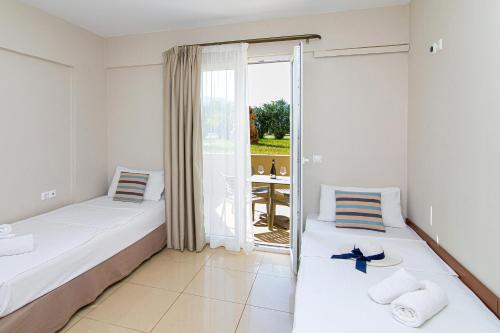 two beds in a room with a balcony at Theo Star Beach Hotel in Malia