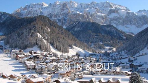 une ville dans la neige avec des montagnes en arrière-plan dans l'établissement Hotel Acadia - Adults Mountain Home, à Selva di Val Gardena