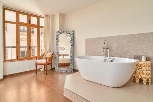 bagno con grande vasca bianca e specchio di Luxury 1st floor apartment in Nerja a Nerja