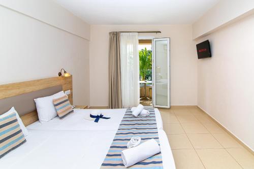 a bedroom with two beds and a balcony at Theo Star Beach Hotel in Malia