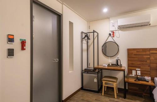 um quarto com uma secretária, um espelho e uma porta em Seogwipo The Hotel em Seogwipo