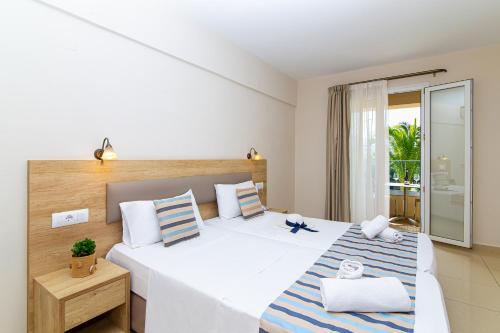 a bedroom with a large white bed with blue and white pillows at Theo Star Beach Hotel in Malia