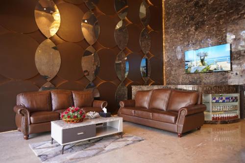 a lobby with two brown leather couches and a table at Pruthvi Paradise in Tumkūr