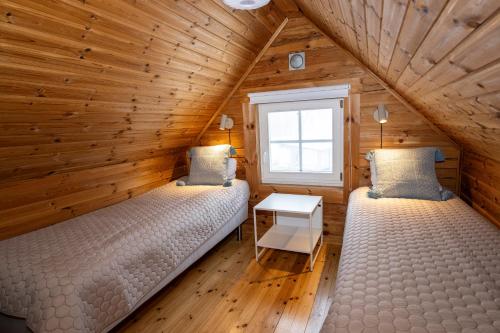 two beds in a room with wooden walls at Västervik Resort in Västervik