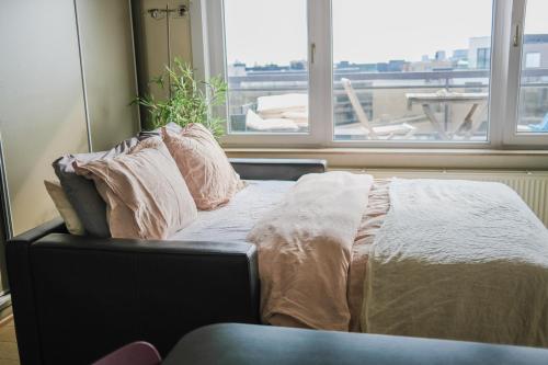 - un lit avec des oreillers dans une chambre avec une fenêtre dans l'établissement holiday vibes! penthouse-studio near beach, à Ostende