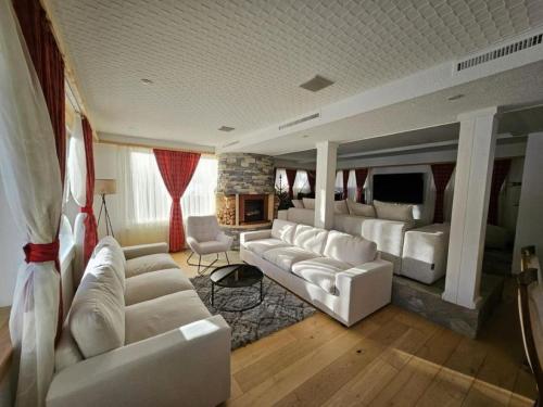 a living room with white couches and a fireplace at Chalet Familial Sublime in Crans-Montana