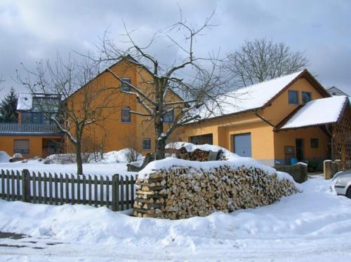 a house with a pile of snow next to a fence at Ferienwohnung Kollmer in Ebern