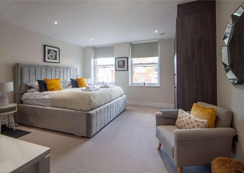a bedroom with a bed and a couch and a chair at Kensington High Street One Bed in London