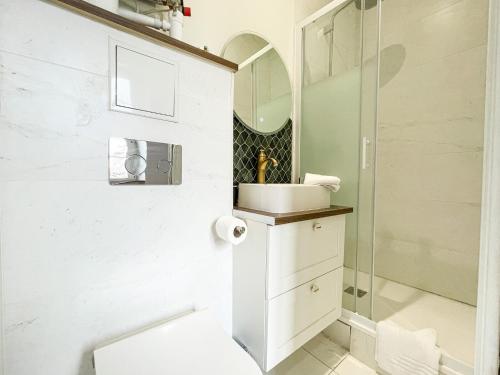 een witte badkamer met een wastafel en een douche bij Bel appartement, offrant calme et luminosité, proche Côte des Basques in Biarritz