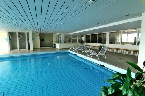 a large swimming pool with chairs in a building at Apartment C46 "Valentine" im Haus Feldbergblick, Lenzkirch, Hochschwarzwaldkarte, Innenpool, Sauna in Lenzkirch