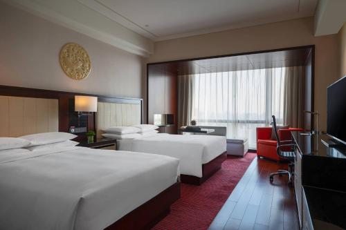 una camera d'albergo con due letti e una grande finestra di Renaissance Beijing Capital Hotel a Pechino