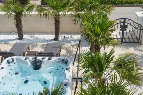 a table and chairs in a courtyard with palm trees at Jakuzzi Vila Suartini Orebić in Orebić