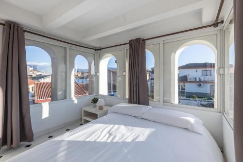 una camera bianca con ampie finestre e un letto di AA Guest - Torreón del Jardín de Sierra Nevada ad Alhendín