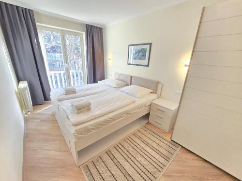 ein Schlafzimmer mit einem Bett und einem großen Fenster in der Unterkunft Dünenpark Binz - Klassik Ferienwohnung mit 1 Schlafzimmer und Balkon im Dachgeschoss 271 in Binz