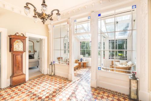 a hallway with a clock and a room with windows at Garth Lodge with Tennis Court and Pool in Wimborne Minster