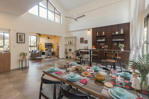 a dining room and living room with a table and chairs at SaffronStays The Totem in Lavasa