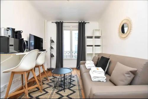 un salon avec un canapé, une table et des chaises dans l'établissement Cosy Studio Neuilly, à Neuilly-sur-Seine
