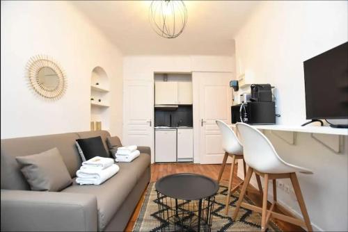 un salon avec un canapé, une table et des chaises dans l'établissement Cosy Studio Neuilly, à Neuilly-sur-Seine