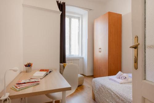 Kleines Zimmer mit einem Schreibtisch, einem Bett und einem Tisch. in der Unterkunft Palladio due - spazioso 3 camere in Triest