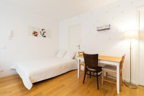 1 dormitorio con cama, escritorio y mesa en Cosy flat close to Arc de triomphe, en París