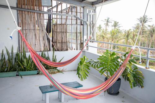 a hammock on a balcony with palm trees at Dulan Tranquilo Hostel都蘭晃輕鬆青年旅舍咖啡館 in Donghe